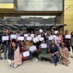 A group of people holding certificates outside a building